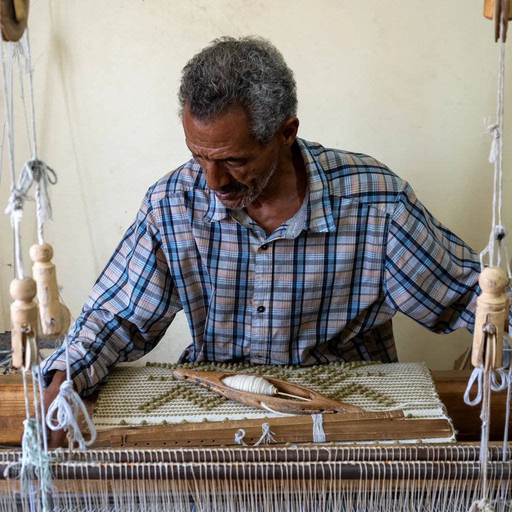 Artisane tissant un tapis sur un métier à tisser traditionnel dans l'atelier de la coopérative à Tamesloht